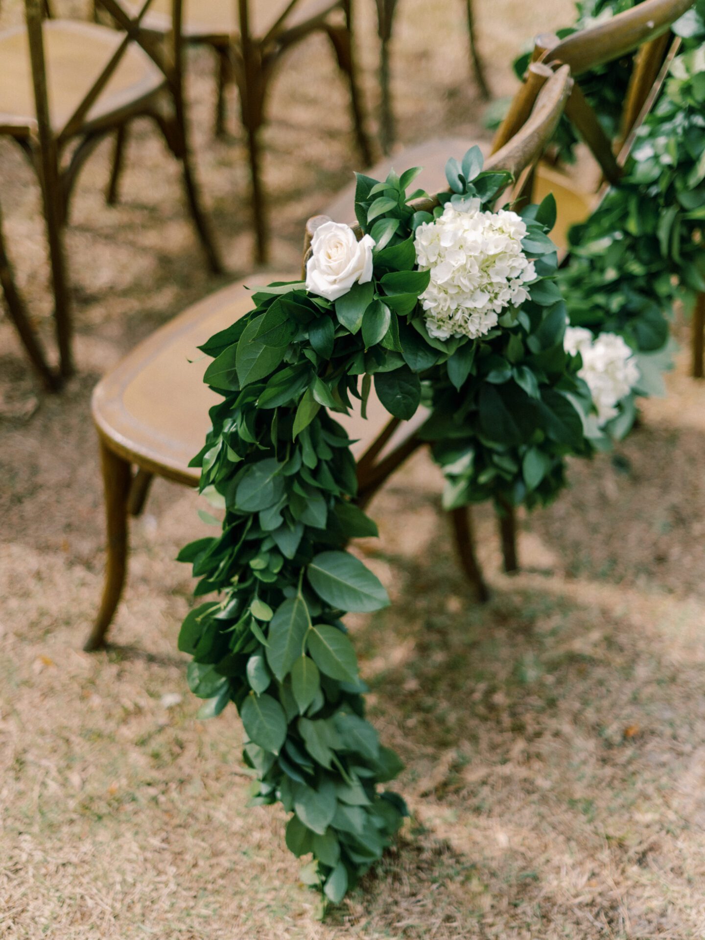 An outdoor ceremony with greenery and white flowers.