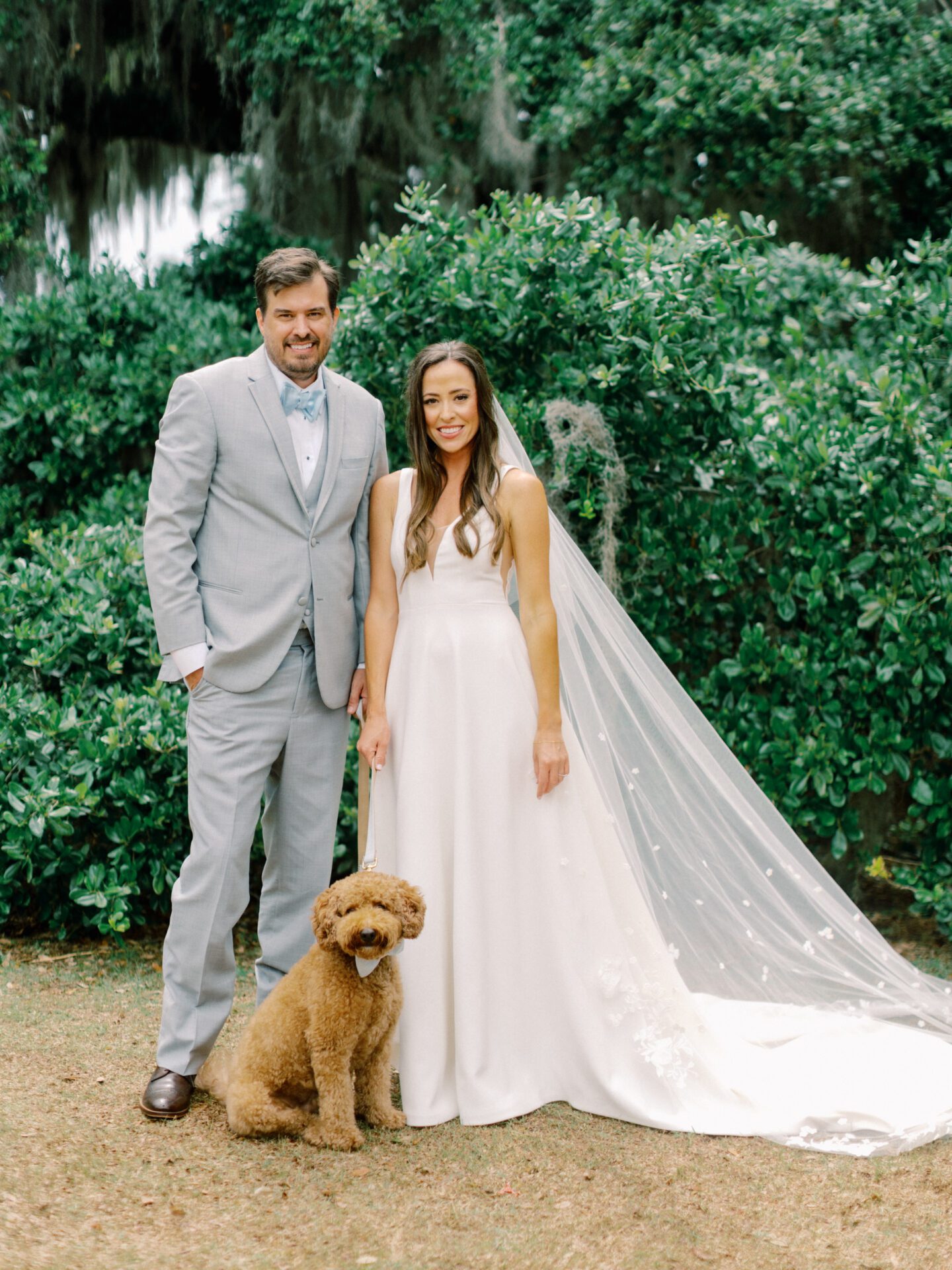 a bride and groom with their brown dog